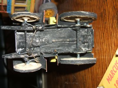marcus 1873
la commande de direction des roues avant (bâtons de cotons tiges et fil de fer trouvé par terre). des petites rondelles en plastique faites à  la main et collages à  l'araldite empêchent les biellettes de se décrocher.
Depuis que j'ai pu voir la vraie en photo sur internet, je sais que mon choix de disposition du moteur et de la boite à vitesses était trop moderne. Tant pis !
